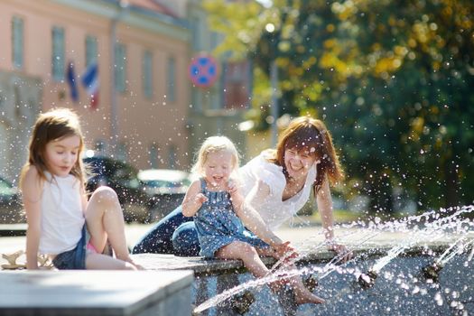 Young woman and two kids by a city fountain
