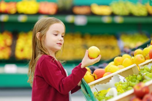 Little girl choosing an apple in a store