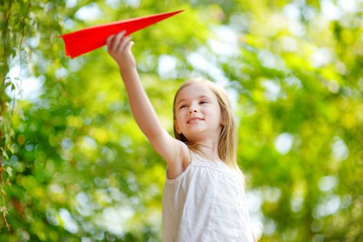 Adorable little girl holding a paper plane