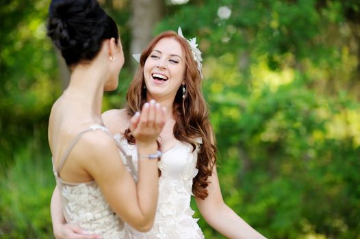 Young bride and her bridesmaid hugging