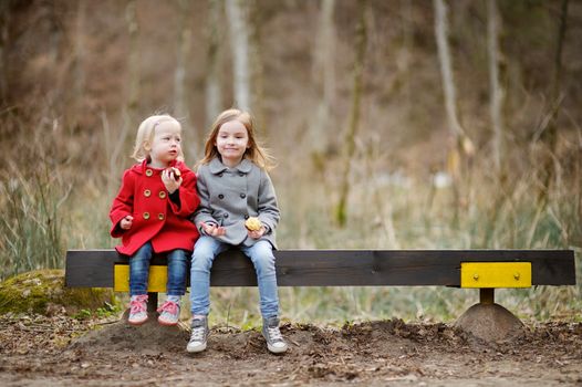 Two little sisters sitting on a bench