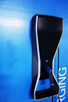 Black modern charging machine car on the blue wall. High tecchnology for ca electric charging. Green energy Inovation.