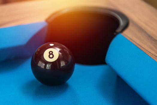 pool or billiards balls on light blue table , focus on number 8