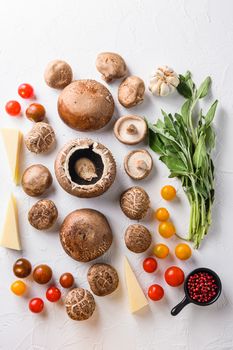 Portabello mushrooms ingredients for baking, cheddar cheese, cherry tomatoes and sage on white background, top view.
