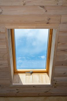 Window in the attic of a wooden house. Window in the middle of the house. The sky is visible from the window