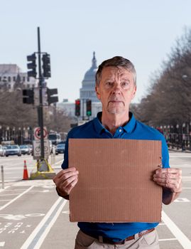 Senior man holding a blank cardboard sign in Pennsylvania Avenue, DC