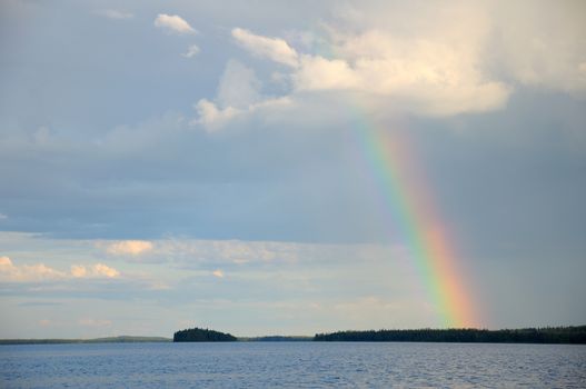 Colorful rainbow under single cloud over lake