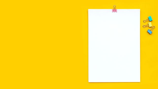 White paper with paperclip on yellow background. 