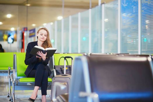 Woman in international airport terminal, reading book