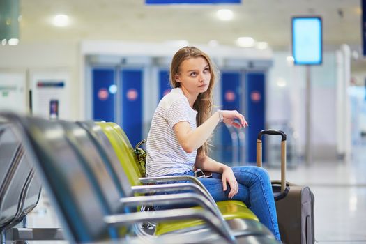 Tourist girl in international airport, waiting for her flight, looking upset