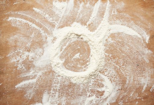 white wheat flour scattered on a brown wooden table