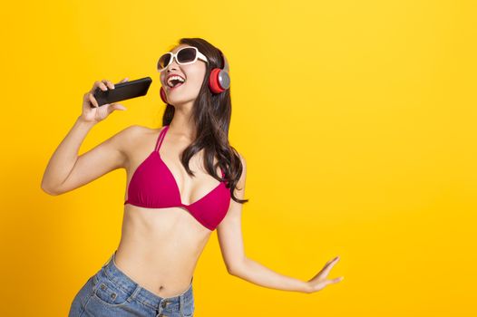 beautiful woman wearing swimsuit bikini and singing by mobile phone