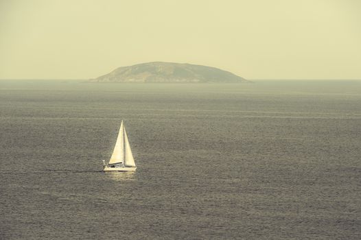 A sailboat navigating  alone in the sea