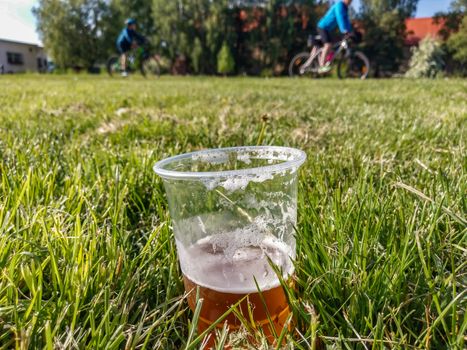 half drunk cup of beer on green grass