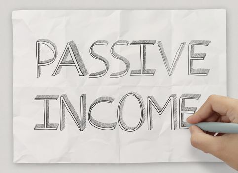 close up of hand drawing passive income on crumpled paper backgr