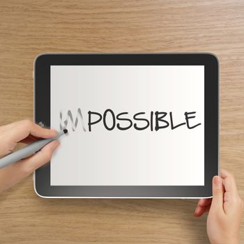 hand changing the word impossible to possible with stylus eraser