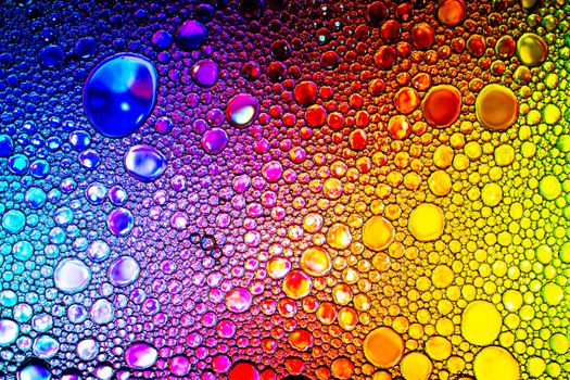 Colorful drops of oil on the water. Rainbow or spectrum colored circles. Abstract bright background for design.