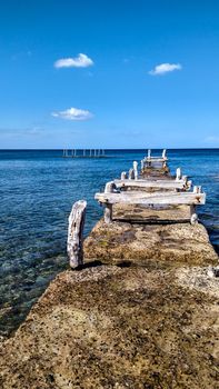 Ancient disused pier with wooden structures corroded by the atmospheric events that made it white on the crystal clear blue sea