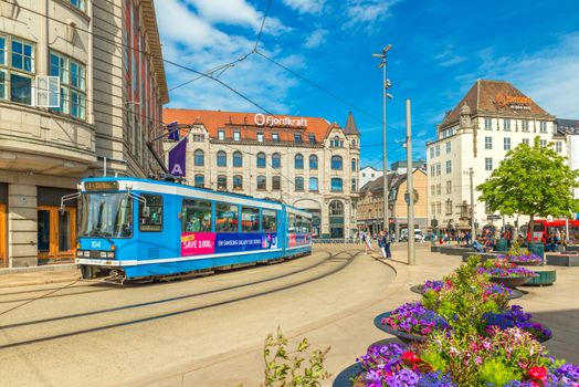 Oslo - June 2019, Norway: View of a street with a blue tram, old historical buildings and beautiful flowerbeds in the center of Oslo