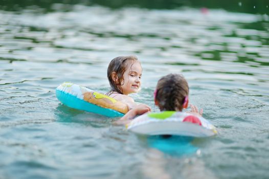 Little sisters having fun swimming in a lake