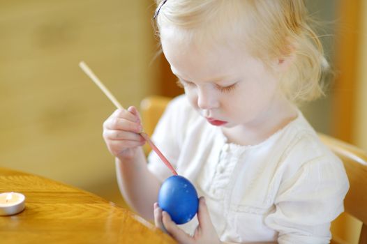 Adorable little girl coloring an Easter egg