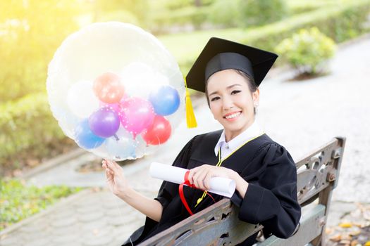 Portrait of happy young female graduates in academic dress and s