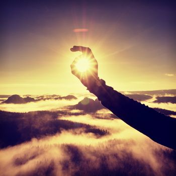 Man hand touch Sun. Misty daybreak in a beautiful hills. 