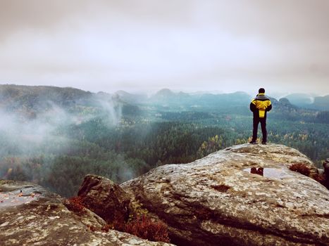Rear view of hiker in yellow black jacket on mountain  while enjoying daybreak