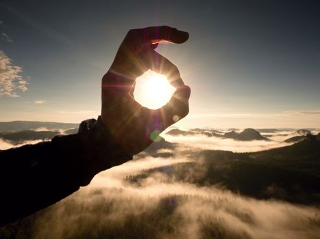 Man hand touch Sun. Misty daybreak in a beautiful hills. 
