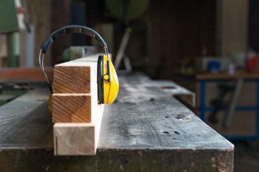 protective yellow headphone on wooden prism in joinery