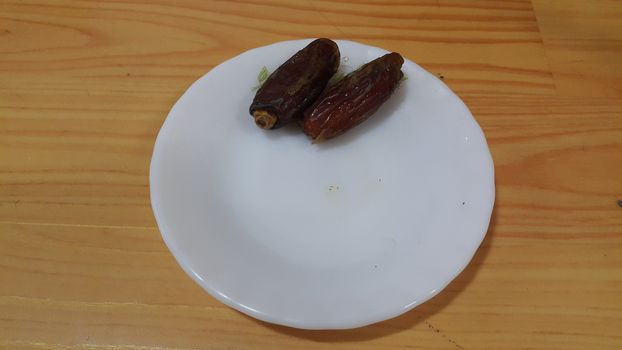 Close up view of fresh dried date palm served in ceramic small white plate