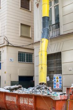 Loaded dumpster near a building in renovation
