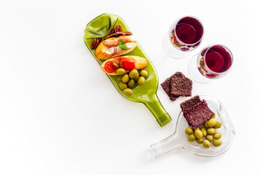 Antipasto on glass bottle plate and red wine in glasses top-down copy space