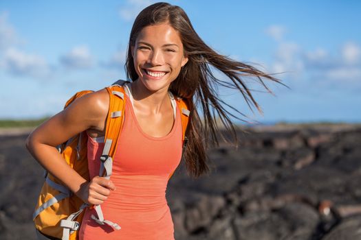 Happy backpacking girl tourist on travel adventure. Young hiking Asian backpacker woman hiker walking on lava rocks in Hawaii near Kilauea volcano. Active lifestyle