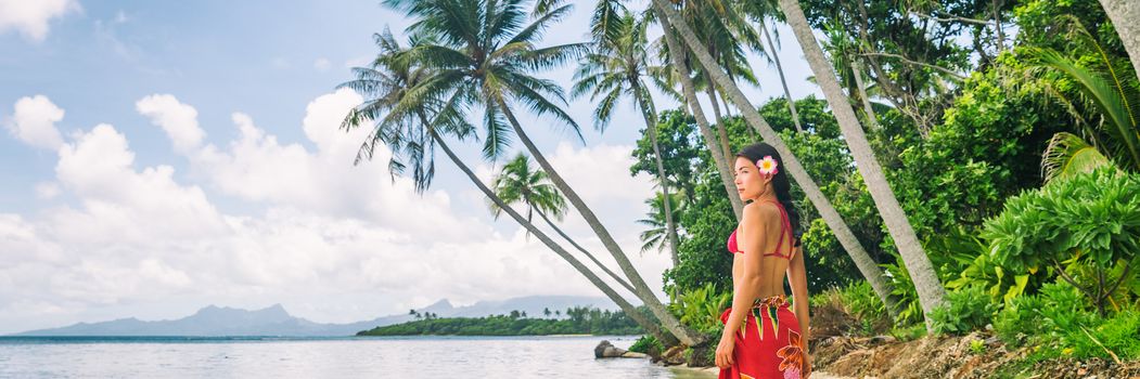 Tahiti luxury exotic travel vacation girl with polynesian flower walking on beach landscape with palm trees. Asian woman in red bikini and beachwear banner panorama