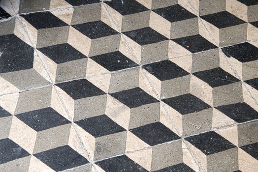 Old marble tiles form a geometric mosaic in black and white