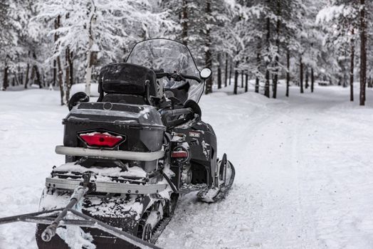 Black frost coated snowmobile on a snow covered forest trail
