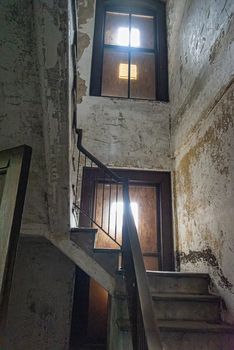 wooden stair case in boarded up, dilapidated house