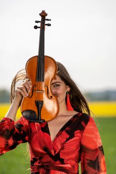 Portrait of a positive young woman. Part of the face is covered by the neck of the violin