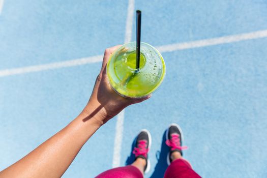 Runner drinking a green smoothie on running track