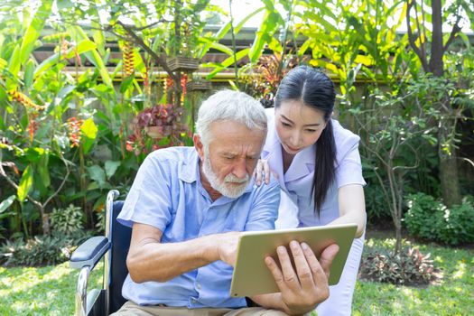 Nurse help senior retirement man working with laptop in backyard at home