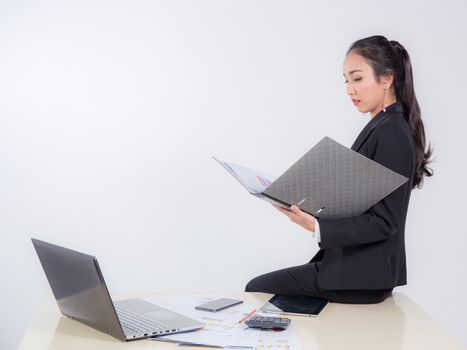 businesswoman by file looking document with sitting table in off