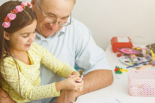 Caring grandfather doing home assignment together with granddaughter