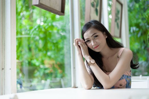 Asian pretty girl has relaxing with happy and smiling at Little Tree Garden cafe, Nakhon Pathom province, Thailand in the morning.