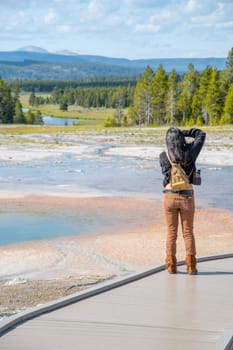 Back view of female tourist taking images of Yellowstone Nationa