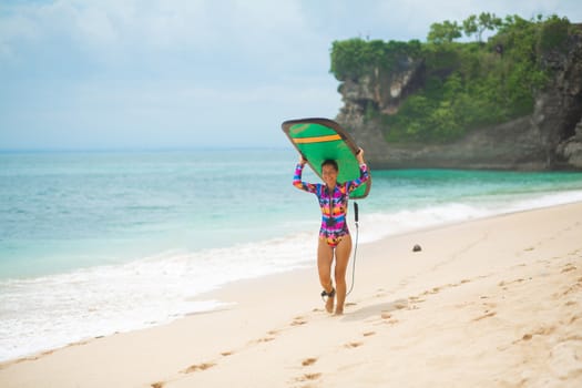 Sexy slim girl with surf board on tropical sand beach. Healthy active lifestyle in summer vocation.