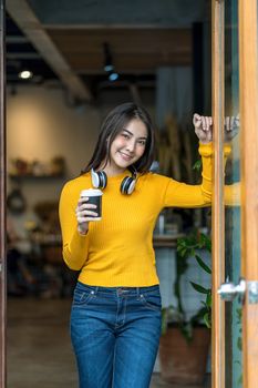 Asian young female holding a cup of coffee in modern coffee shop