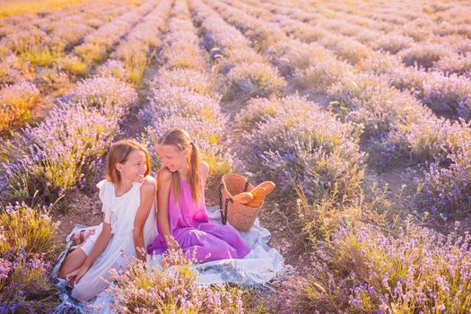 Kids in lavender flowers field at sunset in white dress and hat