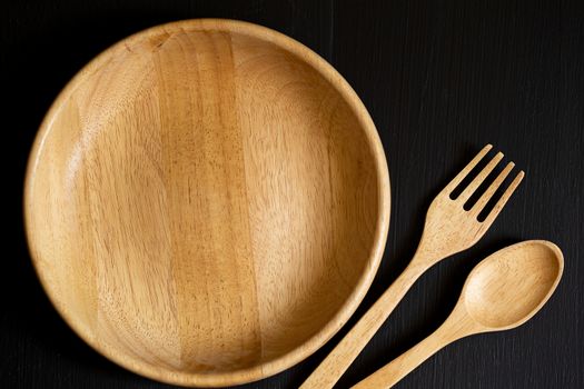 Spoons, forks and Dish made of wood on the black wooden backgrou