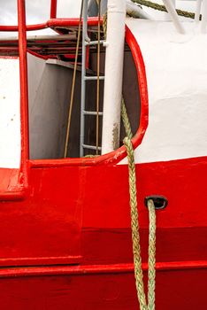 Mooring line of a trawler on a red ship hull